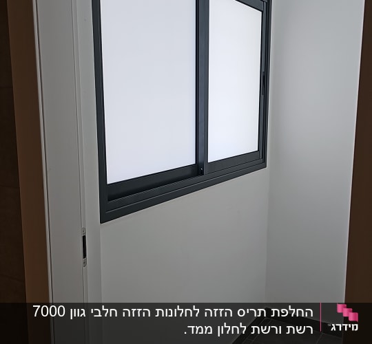 חלון אלומיניום עם מסגרת כהה על קיר לבן